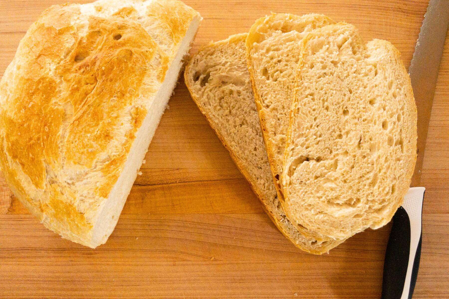 A loaf of bread on a cutting board next to a knife.