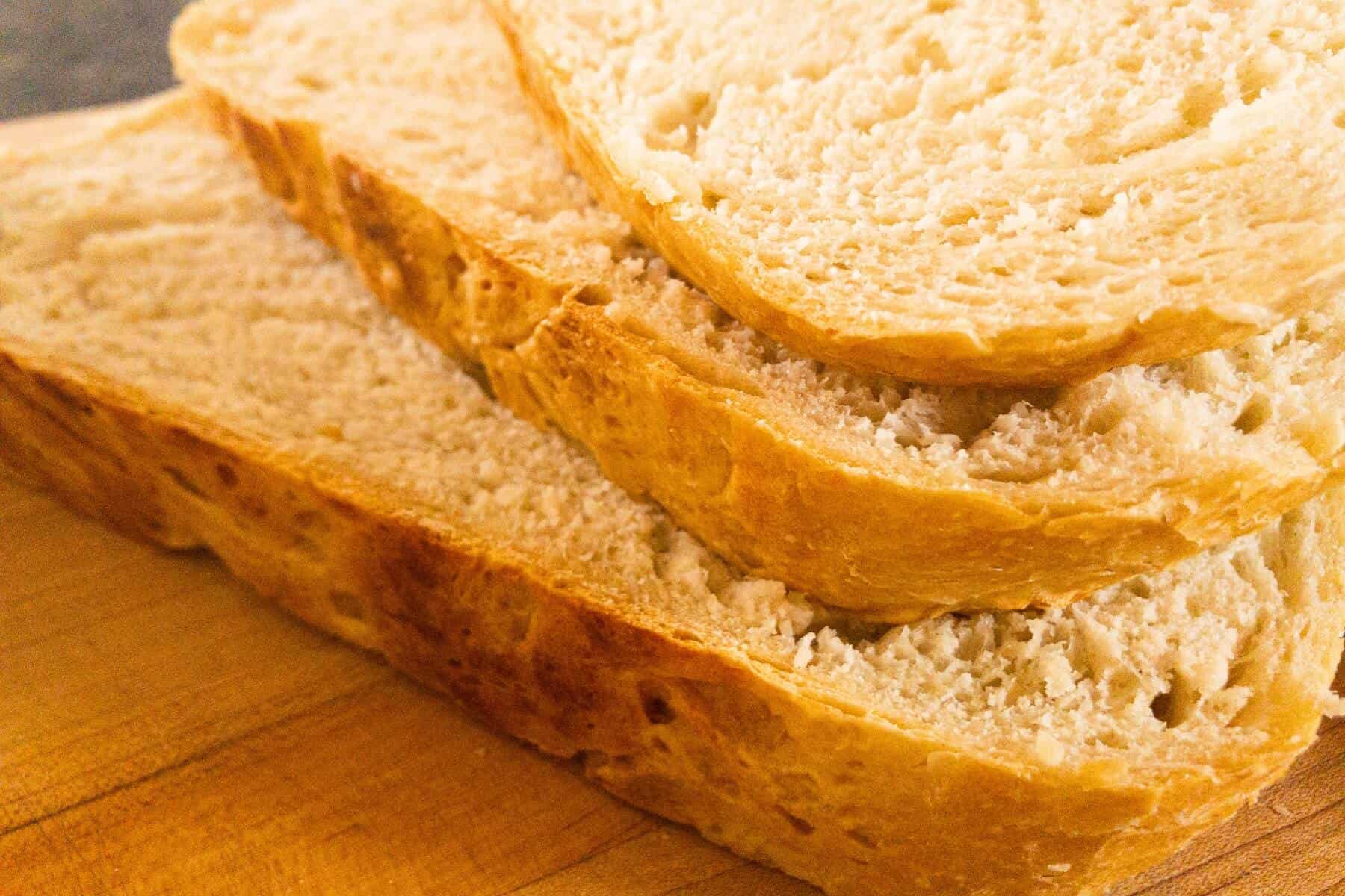 Slices of artisan bread stacked on a cutting board.