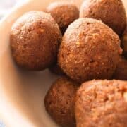 A bowl of brown quinoa date balls sitting on a table.