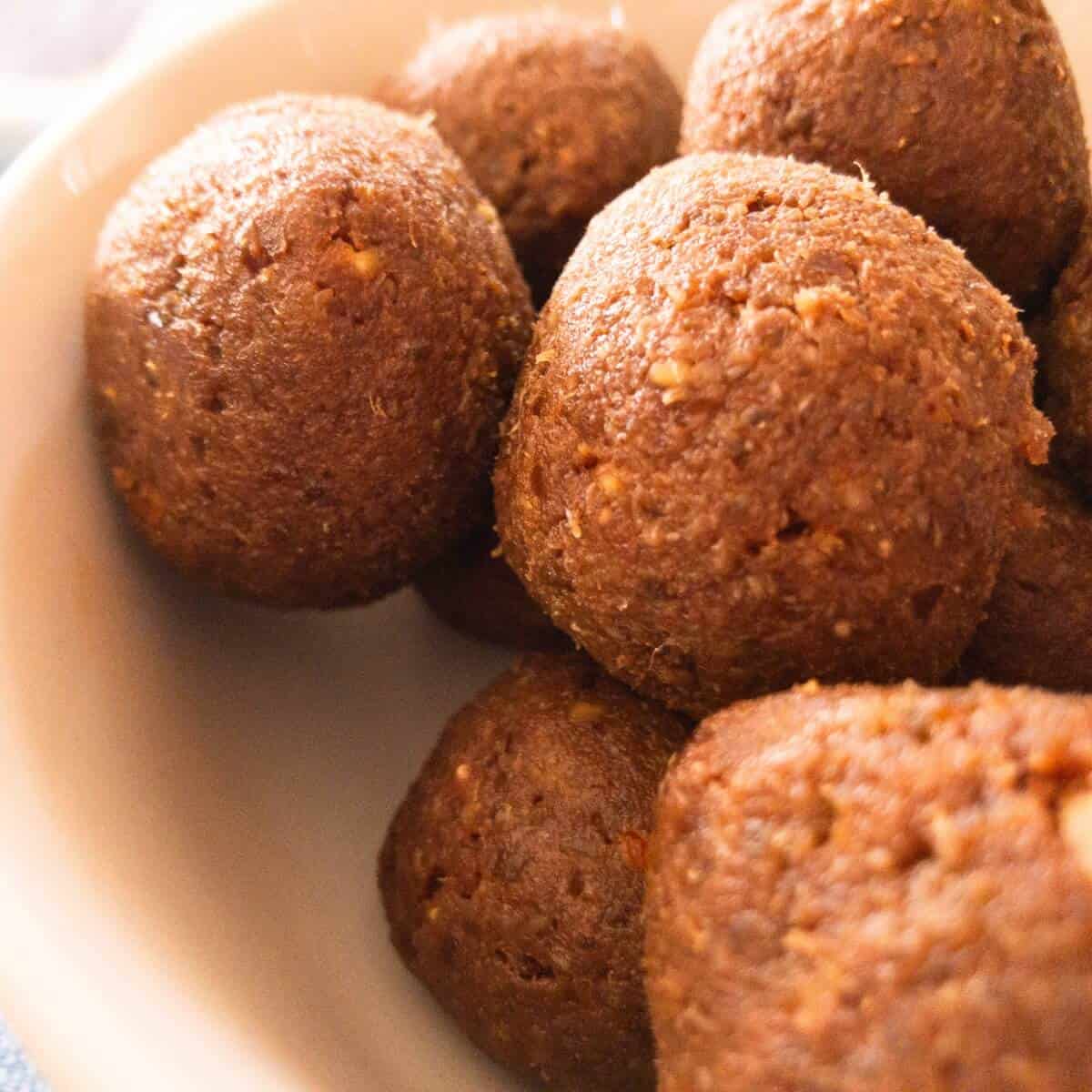 A bowl of brown quinoa date balls sitting on a table.