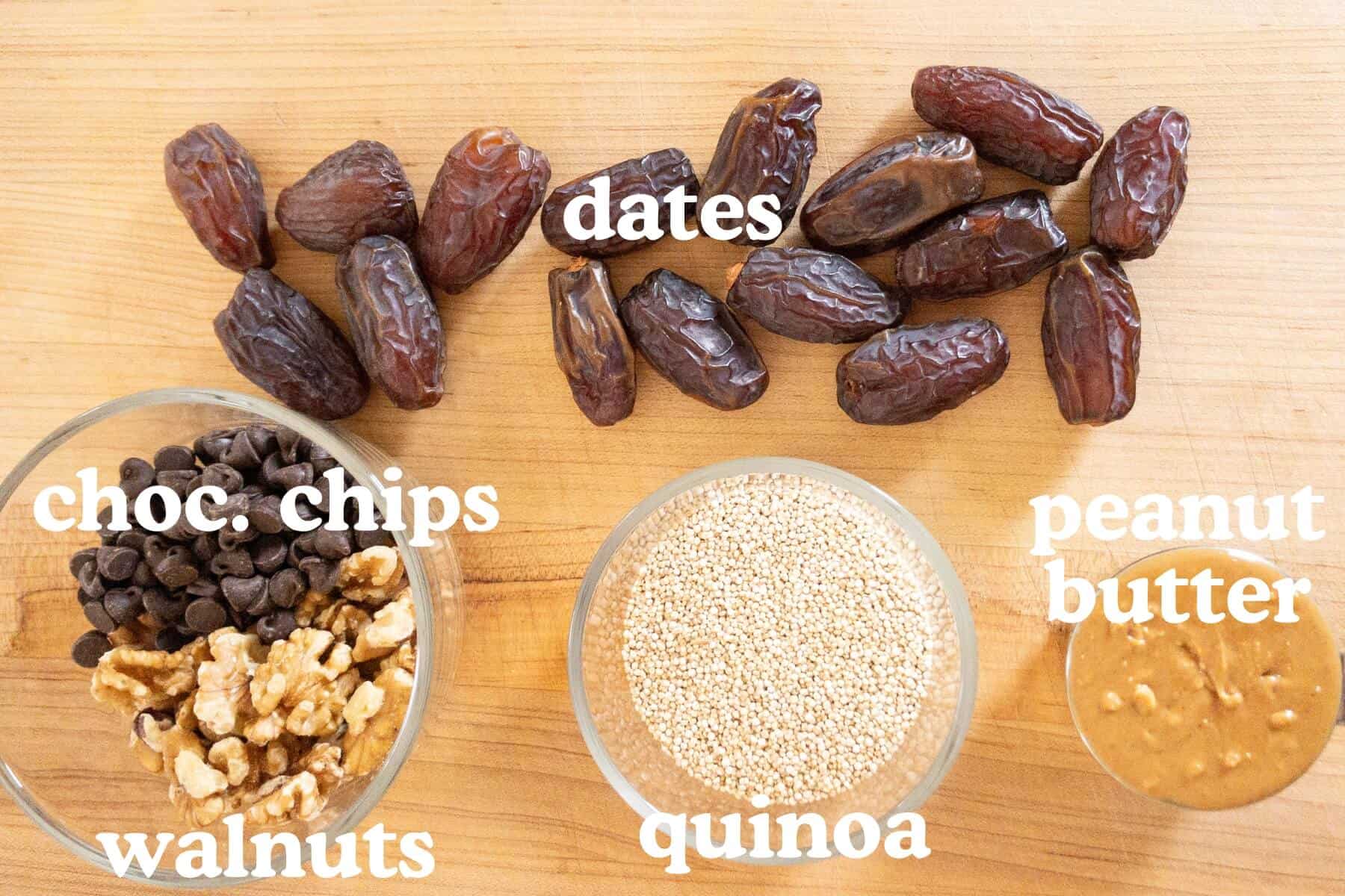 Dates, chocolate chips, walnuts, quinoa, and peanut butter displayed on a wooden board.